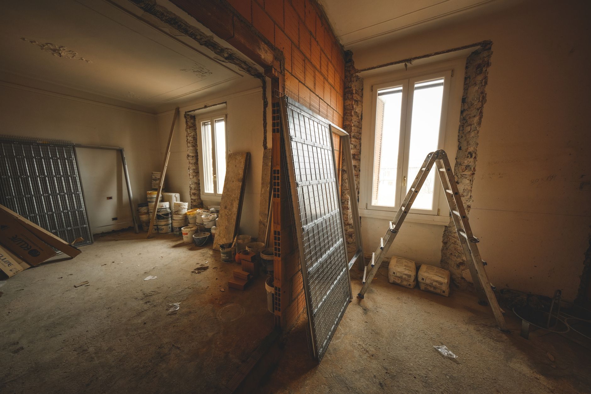 Vue intérieure d'une pièce en rénovation avec des matériaux de construction et une échelle.
