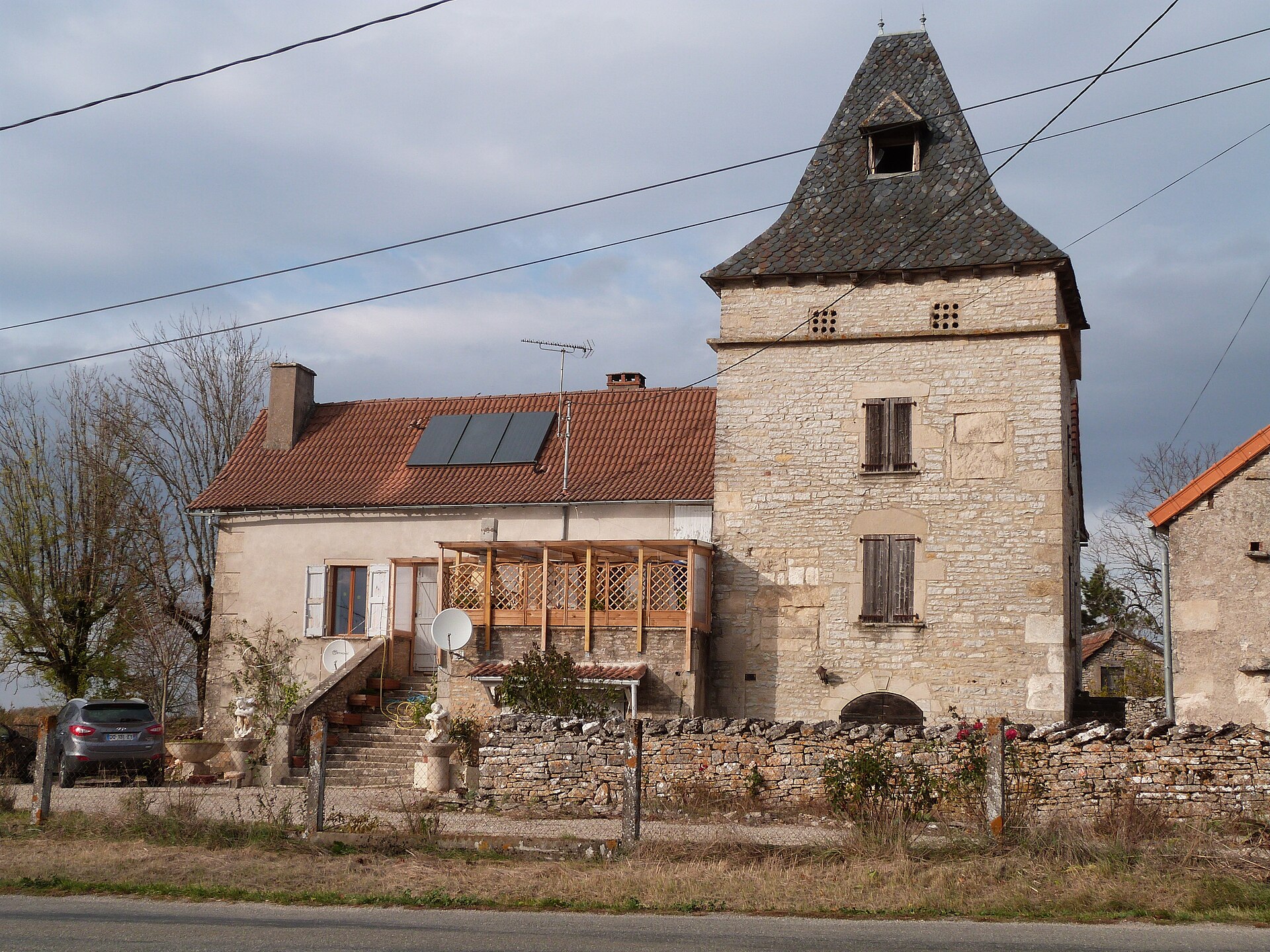 Maison rurale en pierre au toit de tuiles, accolée à un pigeonnier carré à toiture sombre en pointe
